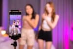 Asian and mixed race  female influencer shooting dance video for social media on mobile phone, having fun at home. To share video to social media application..