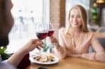 Loving millennial couple toasting red wine, saying cheers, celebrating Valentine’s Day in restaurant